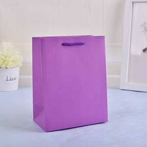 Detail of purple paper gift bag with matching handles in a cozy home setting