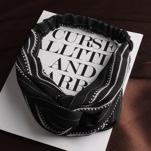 Detail of black fabric headband with white abstract geometric stripes and knot design