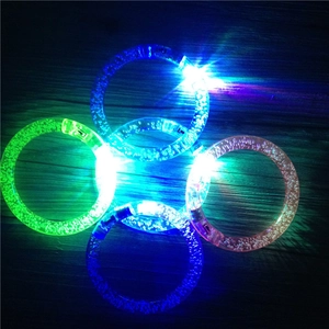 Close-up of colorful glowing LED acrylic bubble bracelets on a dark wood background