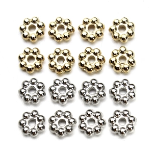 Detailed grid of gold and silver flower-shaped spacer beads for DIY jewelry making