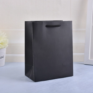 Detail of a matte black paper gift bag featuring durable black braided rope handles