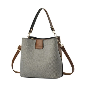 Elegant woven shoulder bag with brown leather handles and adjustable crossbody strap