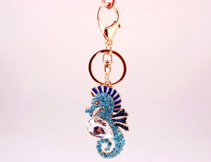 Close-up of rose gold seahorse keychain with blue crystals and sparkling teardrop gem