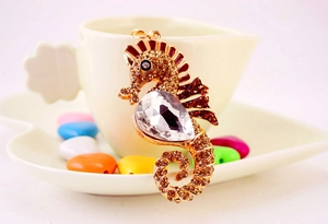 Macro detail of seahorse keychain with brown crystals and drop-shaped gemstone