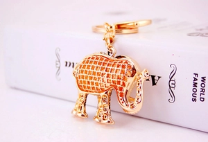Close-up of golden elephant keychain with hollow patterns on a white book surface