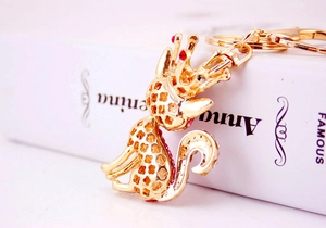 Macro detail of golden fox keychain with crown and red rhinestones on book surface