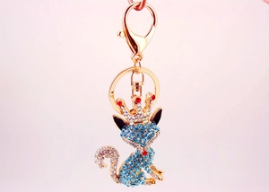 Detail of blue rhinestone fox keychain with gold crown and red crystal accents