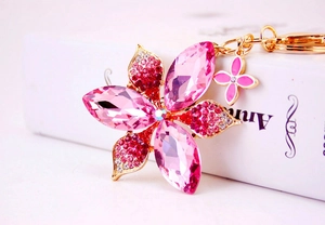 Close-up of pink crystal flower keychain with gold metal base and small clover charm