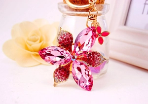 Close-up of pink crystal flower keychain with gold metal base and butterfly charm