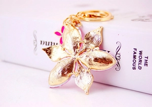 Macro shot of gold four-leaf flower keychain with pink accents and sparkling crystals