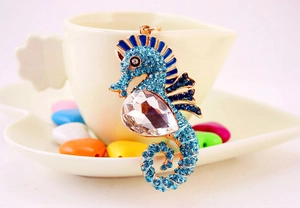 Close-up of seahorse keychain with blue rhinestones and transparent crystal on golden metal