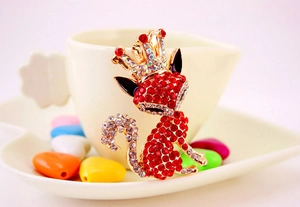 Macro shot of a gold-plated fox brooch with red rhinestones and a sparkling crown