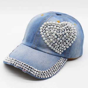 Detail of light blue denim baseball cap with heart-shaped pearls and rhinestone brim