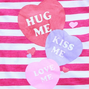 Detail of pink and white striped pet vest featuring heart prints and Kiss Me text