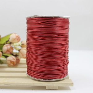 Roll of red waxed cord for DIY jewelry making on white spool and wooden stand