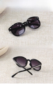 Detail of round black children's sunglasses with silver metal arrows and purple lenses