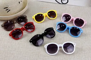 Flat lay view of colorful kids round sunglasses in seven colors on a textured background