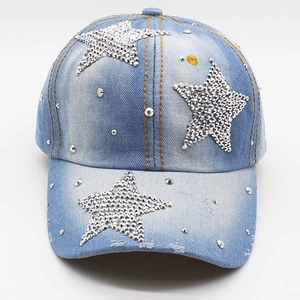 Detailed close-up of washed blue denim baseball cap with rhinestone stars and silver studs
