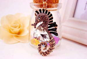 Close-up of seahorse keychain with purple rhinestones and large crystal on gold metal