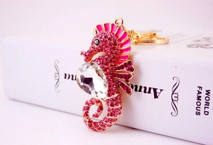 Close-up of golden seahorse keychain with pink rhinestones on a white book cover