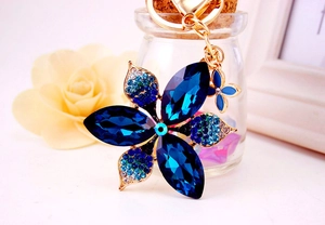Detailed close-up of blue crystal flower keychain with gold four-leaf clover pendant