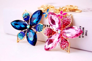 Detailed shot of two metal floral keychains with blue and pink crystals and small rhinestones