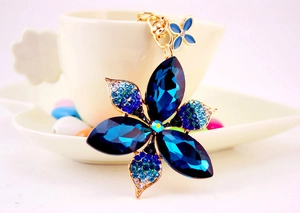 Close-up of a sparkling blue crystal flower keychain with elegant golden metal hardware