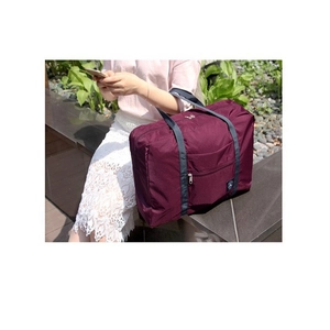 Outdoor view of a large burgundy waterproof travel bag with reinforced straps on a stone bench