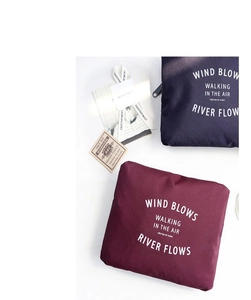 Detail of waterproof foldable travel bags in navy and burgundy ripstop nylon fabric