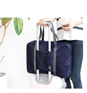 Detail view of deep blue foldable travel bag attached to a suitcase telescopic handle