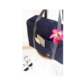 Detail of navy blue waterproof travel bag showing front zipper pocket and passport storage