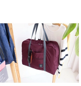 Close-up of burgundy waterproof travel bag with grey handles on a wooden hanger