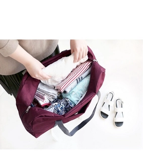 Macro view of burgundy travel organizer bag being packed with clothes on white background