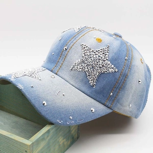 Detailed macro view of denim baseball cap with rhinestone star and yellow stitching