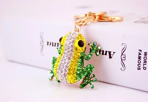 Detail shot of a golden metal frog keychain with yellow and green crystal rhinestones