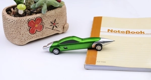 Detail shot of a green metallic racing car pen lying on an open notebook on a desk