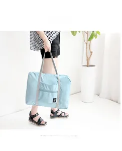 Close-up of light blue waterproof folding travel bag with wide gray straps and front pocket