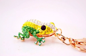 Close-up of golden frog keychain with sparkling green and yellow crystal rhinestones