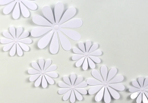 Flat lay of multiple white daisy wall decals in various sizes on a clean background