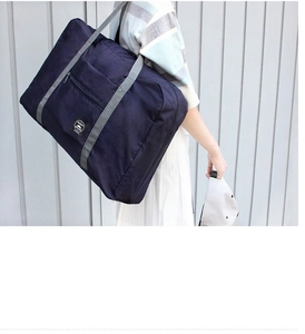 Practical large blue folding travel bag being worn over the shoulder for size demo