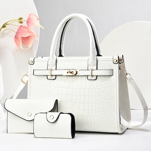 Detailed view of 3-piece white crocodile pattern handbag set with golden hardware