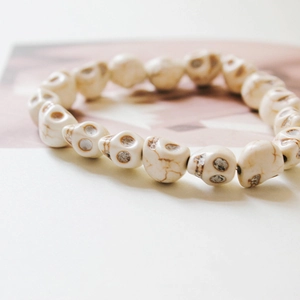 Detailed close-up of cream synthetic turquoise skull beads bracelet on a soft background
