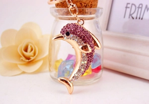 Detailed view of a gold dolphin keychain with purple and white crystal rhinestones