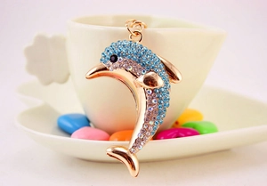 Close-up of golden dolphin keychain with blue and clear rhinestones on a decorative dish