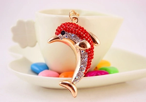 Close-up of golden dolphin keychain with sparkling red and clear rhinestones