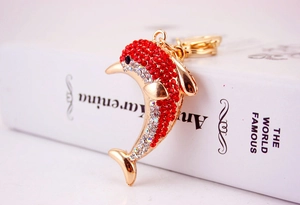 Macro shot of gold dolphin keychain with red and clear rhinestones on white book