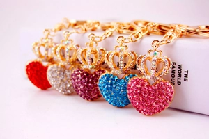 Detailed view of colorful rhinestone heart keychains with crowns on a white book surface