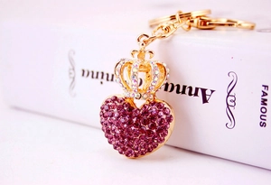 Close-up of golden crown heart keychain with purple rhinestones on a white book