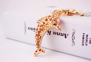 Detailed close-up of golden dolphin keychain featuring hollow design and pink rhinestones