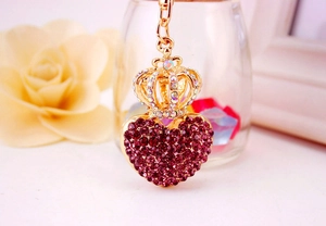 Close-up of golden heart keychain with purple rhinestones and a small crown charm